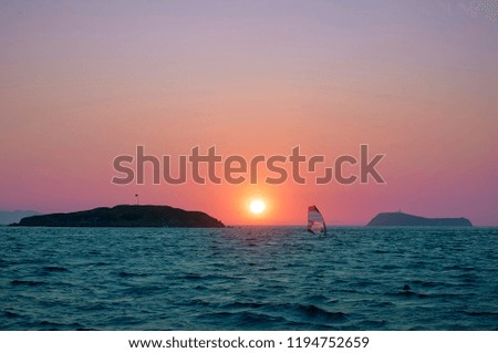 Surfing sailing. Landscape. Sunset on the Turkish coast of the Aegean Sea. View of the island. Orange sky and blue sea. Turgutreis , Bodrum.