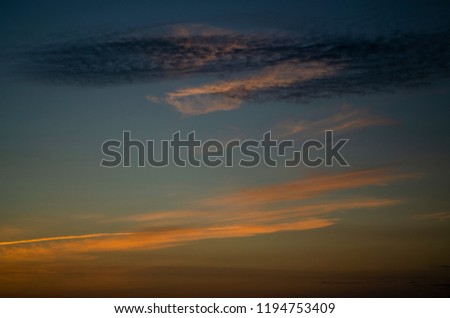 Dramatic colorful clouds at dusk. Yellow stripe, navy blue ripples