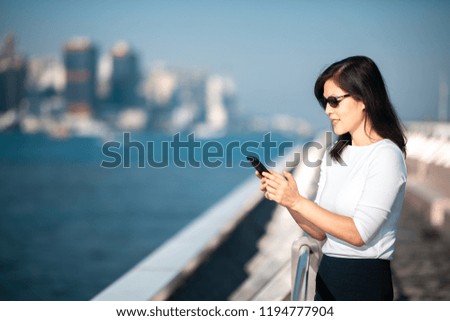 Business woman using the smartphone on waterfront in Hong Kong 