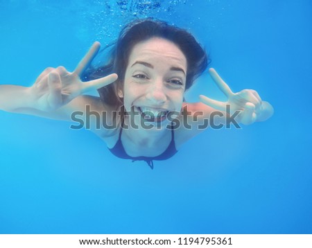 Beautiful young woman swimming in pool, underwater view
