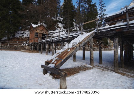 wooden shelter for boats with slide towards the mountain lake with snowy mountains