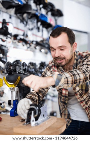 Smiling adult  master fixing roller-skates in sports store