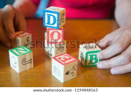 Unidentified people in red cloth playing character letters wooden block on table, relaxing concentrate brain training.