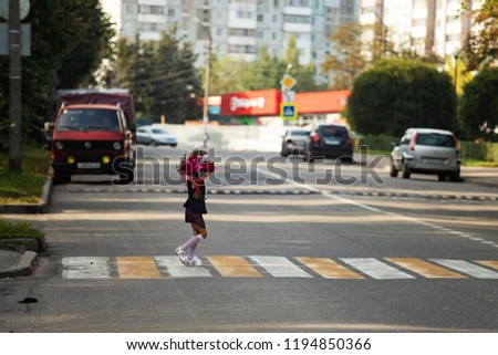 independent girl alone crossing the road on a pedestrian crossing holding a bouquet of flowers, the child goes to school for a holiday, traffic rules
