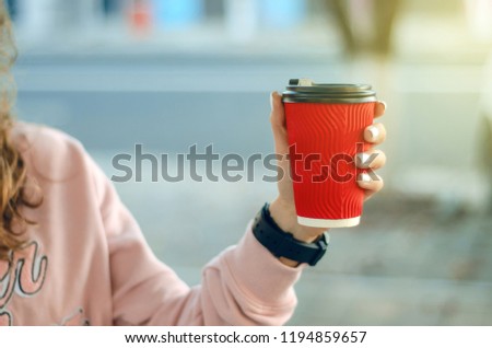 Beautiful woman in jeans and a sweatshirt with coffee in the street