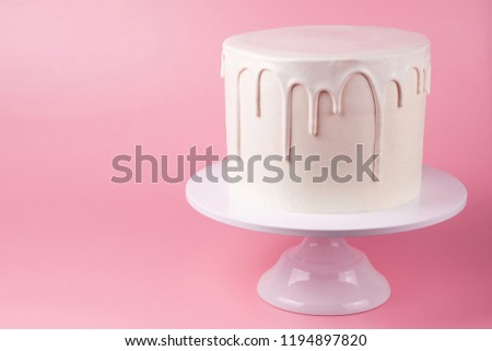 Simple white cake with white glaze on a pink background. Picture for a menu or a confectionery catalog.