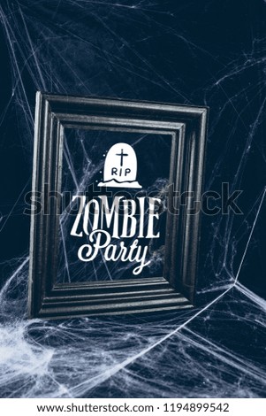 black frame in spider web, creepy halloween decor with "zombie party" lettering
