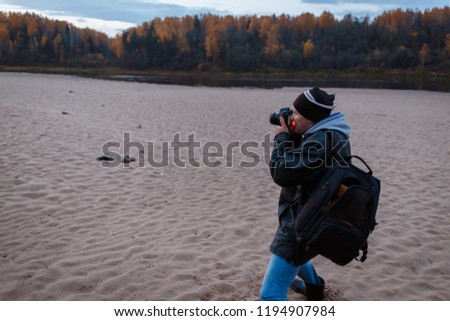 Side view of amateur photographer shooting the autumn scenery of the forest road. Landscape therapy, photo hunting concept