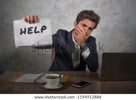 young attractive sad and depressed business man working at office laptop computer desk holding notepad asking for help feeling desperate overwhelmed and exhausted in corporate job lifestyle