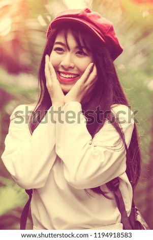 Cheerful young girl wearing white dress and violet hat in the garden, woman lifestyle holiday concept. Vintage tone.
