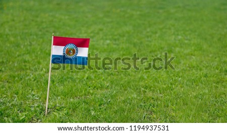 Missouri flag. Photo of Missouri state flag on a green grass lawn background. Close up of state flag waving outdoors.