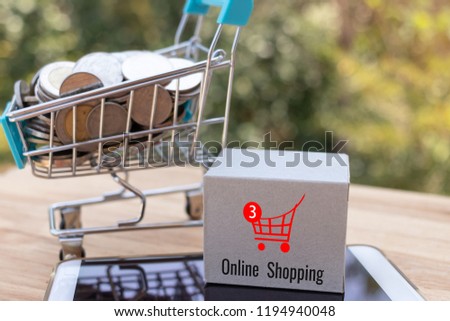 Cardboard box with symbol on smartphone and Thai coins in trolley with nature background. Consumer can buy product anywhere anytime from seller using web browser. Online shopping and ecommerce concept