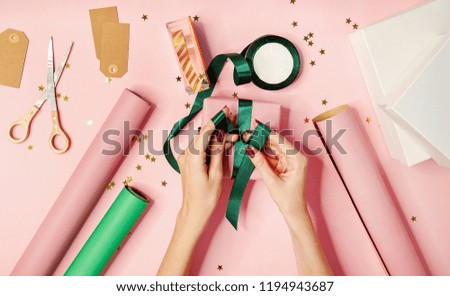 flat lay image of female hands package gifts on pink background. holidays concept