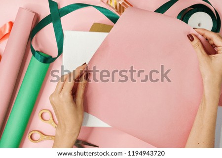 flat lay image of female hands package gifts on pink background. holidays concept, copy space