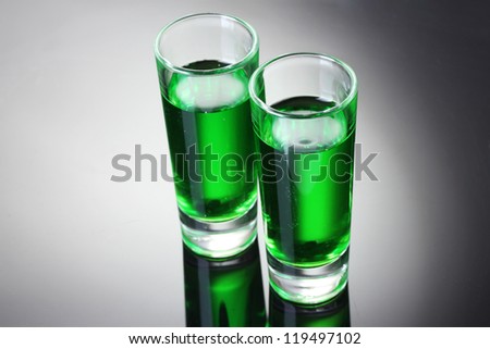 Two glasses of absinthe on grey background