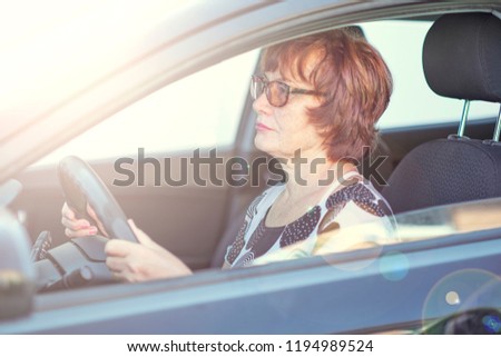 Beautiful smiling elderly woman 55-60 years with white teeth in suit at the whee, Driving a Car Through the mountains