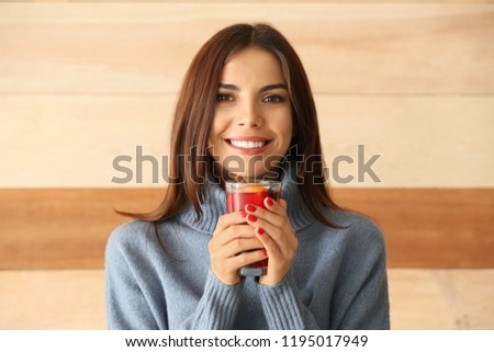 Woman with glass of delicious mulled wine on wooden background