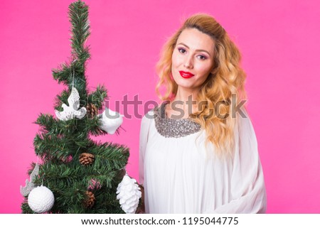 Christmas and holiday concept - Portrait of smiling beautiful blonde woman with Christmas tree on pink background