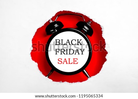 Black friday sale concept. Fourth Friday of November, beginning of Christmas shopping season since 1952. Old alarm clock with text inside torn paper hole. Copy space, close up, top view, flat lay.