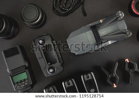 Work space photographer with laptop, digital camera, memory card, action camera, drone, remote controller, phone, VR glasses and accessory. Top view on black table background.  Mockup template