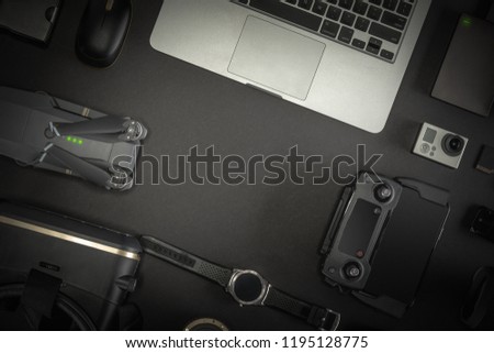Work space photographer with laptop, digital camera, memory card, action camera, drone, remote controller, phone, VR glasses and accessory. Top view on black table background.  Mockup template