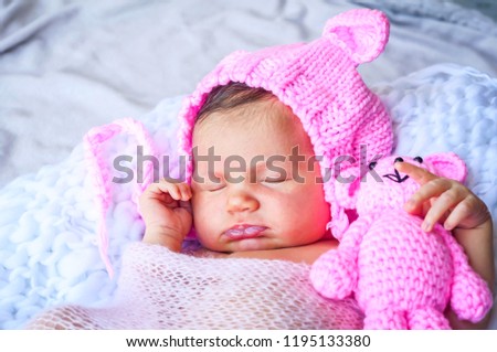 Cute adorable sweet newborn infant girl in a pink funny cap with ears sleeping. Strong and serene newborn baby sleep concept image.