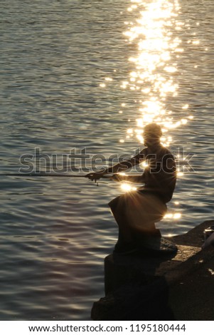 Fisherman with the sun in the coast of Basque Country