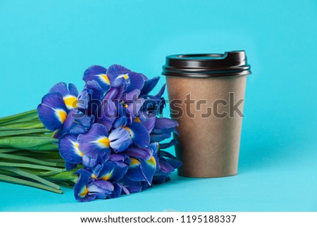 Takeaway paper coffee cup mockup isolated on blue background. Concept photo of coffee cup with iris. Free empty blank copy space for your design text or banner of brand. Trending colors