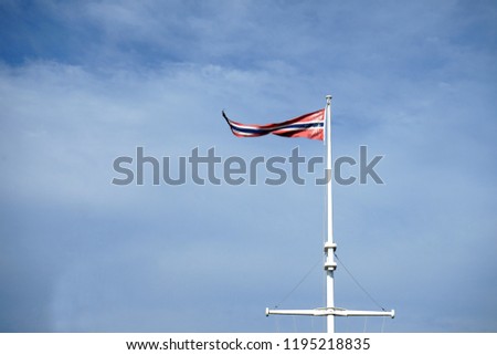 Old Norwegian pennant over cloudy sky at windy weather.