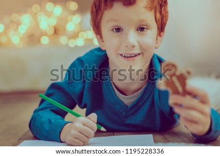 Home task. Portrait of handsome kid that holding pencil and going to draw present for parent
