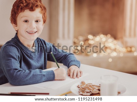 Future talent. Portrait of smiling little boy sitting at the table while using a pencil and drawing a picture