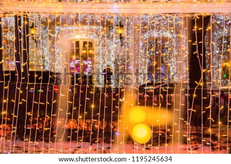 Close up of coloured light bulbs in light tunnel. Christmas street decorations, new year preparation in city. Abstract blurry background.