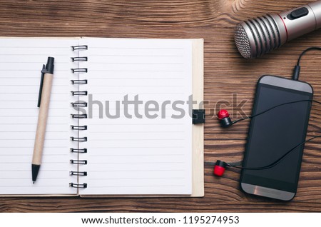 Mobile phone, blank page note pad, microphone and headphones on the table. Audio recording studio concept. Karaoke. Song lyrics. Royalty-Free Stock Photo #1195274953