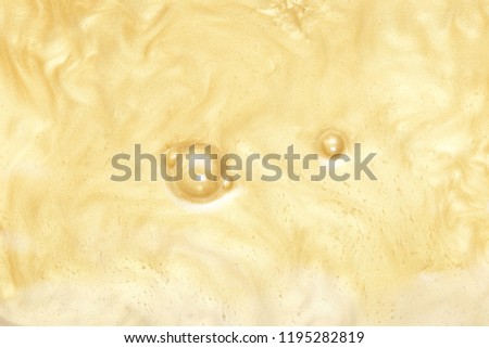 Abstract background, golden paint with waves and currents. sparkling yellow metallic gold. Paint in water with bubbles on the surface