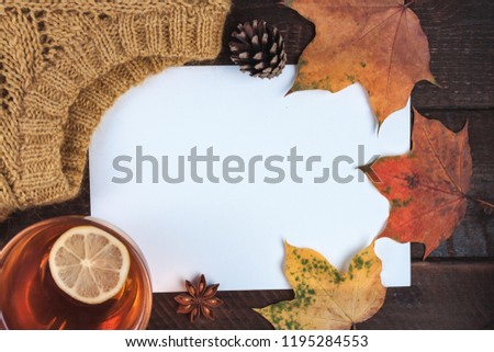 Knitted sweater, autumn, maple leaves and a cup of hot tea with lemon on a wooden background. Winter and autumn clothes. Copy space. Top view. Warm, cozy clothes