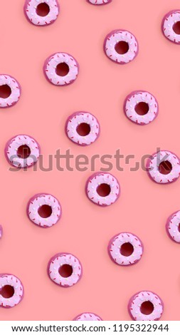 Many small plastic donuts lies on a pastel colorful background. Flat lay minimal pattern. Top view