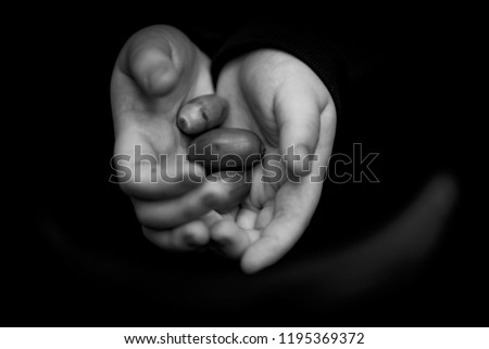 A close up shot of a boy with 3 acorns in his hand taken in black and white