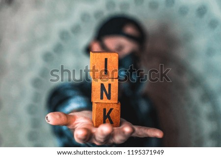 Picture of random letters on wooden cubes levitating in the air with a blury man in a background