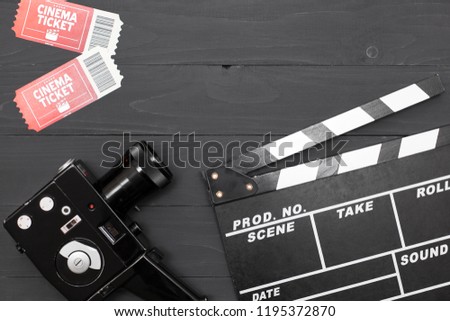 Movie time, flat lay with space for text. Cinema minimal concept. Cinema Clapperboard, retro camera, movie tickets on a black wooden background.