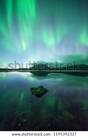 Northern lights reflected on a lake in Kilpisjärvi, Lapland, Finland. Mt.Saana in the background.