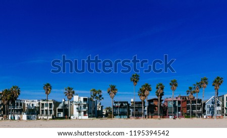 Houses and palm trees along Venice Beach, under blue clear sky, in Los Angeles, USA Royalty-Free Stock Photo #1195394542