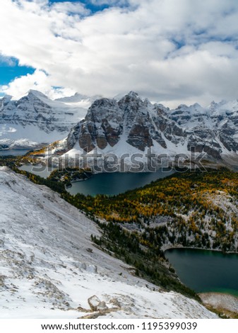 Distant alpine peaks covered in snow towering over autumn valleys of larches