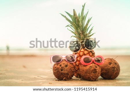 Pineapple and Coconuts Wearing Sunglasses On Sandy Beautiful Beach