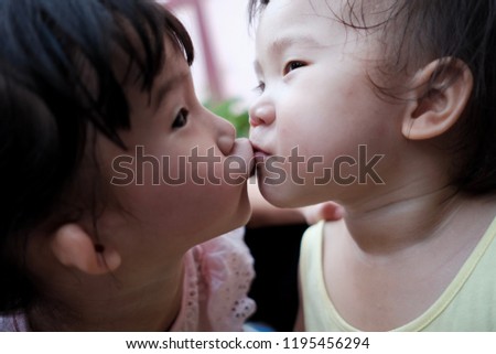 Two sisters are kissing each other with love.