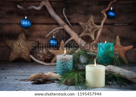 Beach scene of Christmas candles and seaside decor with blue ornaments on a wooden background