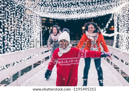 Mother with her daughter and friend enjoying in ice skating.