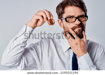a man with glasses holding his beard and holding Bitcoin cryptocurrency                           