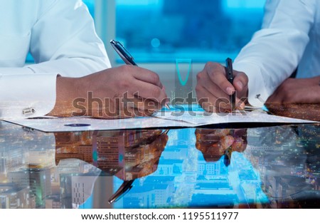 Businessmen hands signing documents on Riyadh skyline city scape background multi exposure
