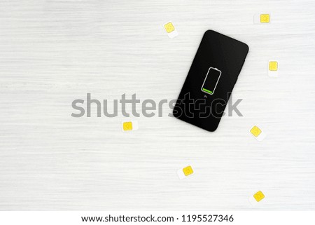 Scattered SIM cards and phone with low charged battery on screen
