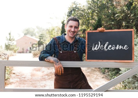 Farmer holding a blackboard welcoming sign